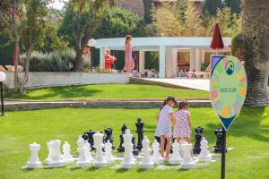 two girls playing a game of chess in a park at St Raphael Resort in Limassol