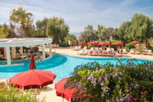 a resort swimming pool with red umbrellas and chairs at St Raphael Resort in Limassol