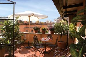 einen Balkon mit einem Tisch, Stühlen und einem Sonnenschirm in der Unterkunft Hotel Novecento in Rom