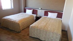 a hotel room with two beds and a ottoman at Kuretake Inn Gotemba Inter Gold Cabin in Gotemba