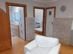 a living room with a white chair and a bedroom at Mazurskie Wzgórze Apartament in Rydzewo