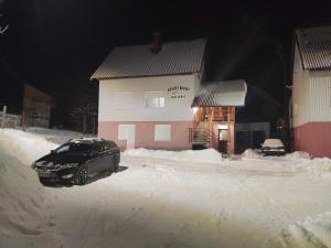 samochód zaparkowany na śniegu przed budynkiem w obiekcie Apartman KALJEVIĆ w mieście Žabljak