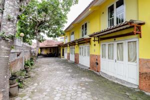 an alley with a yellow building with white garage doors at Hotel Kayu Manis in Kaliurang