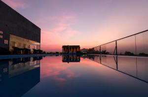 a building with a pool of water in front of a sunset at Regenta SGS Greenotel - Lonavala in Lonavala