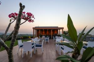 un restaurante con mesas y sillas blancas en una terraza en Regenta SGS Greenotel - Lonavala, en Lonavala