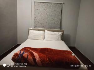 a bed with a red blanket on top of it at Sai Baba Service Apartments in Chennai