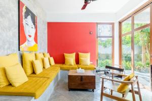 ein Wohnzimmer mit gelben Kissen und einer roten Wand in der Unterkunft Ping Pool Villa 1 in Mae Rim