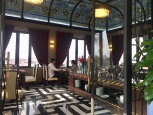 two people sitting at a bar in a restaurant at Hotel du Monde Art in Hanoi