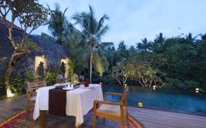 a dining table and chairs on a deck with a pool at D'Legon Luxury Villas in Ubud