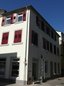 a white building with red shuttered windows on a street at Ferienwohnung Speyer in Speyer