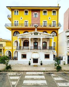 Euro Hotel Iglesias في إيغليسياس: مبنى اصفر وابيض مع شرفة