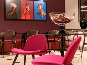 尼什的住宿－嘉尼藝術洛夫特酒店，一张桌子,上面摆放着粉色椅子和一碗水果