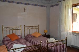 Un dormitorio con dos camas y una cruz en la pared. en Borgo Vecchio, en Montalcino