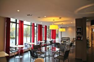 a restaurant with tables and chairs and red curtains at Kyriad Charleville Mezieres in Charleville-Mézières
