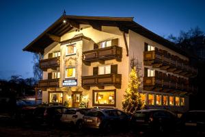 un edificio alto con coches estacionados frente a él en Hotel Garni Entstrasser en Kitzbühel