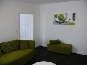 a living room with a green couch and a chair at Ferienwohnung Speyer in Speyer