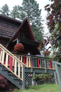 a house with red shutters and flowers on the stairs at Sunny Bluffs Chalets in Kaslo