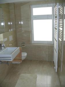 a bathroom with a sink and a toilet and a window at Ferienwohnung Speyer in Speyer