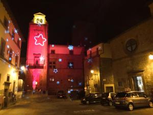 a tall building with a clock tower with christmas lights at Locazione Turistica Vicolo delle Cordonate in Vitorchiano