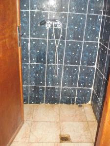 a bathroom with a shower with a black tile wall at Auberge Gitelkst in Tafraout