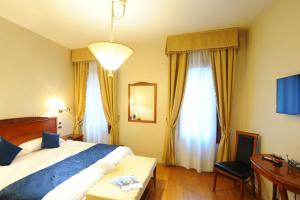 a hotel room with a bed and a desk and windows at Locanda del Ghetto in Venice