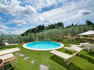 una piscina en un patio con sillas y sombrilla en Apartment Lari-1 by Interhome, en Luiano