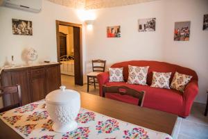 un soggiorno con divano rosso e tavolo di La dimora della Sarta ad Alberobello