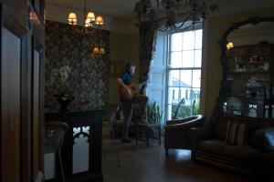 a woman is playing a guitar in a living room at The Grove Falmouth in Falmouth