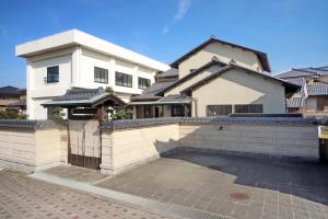 duży biały dom z bramą przed nim w obiekcie 淡路島西海岸の宿 梅木屋 w mieście Sumoto