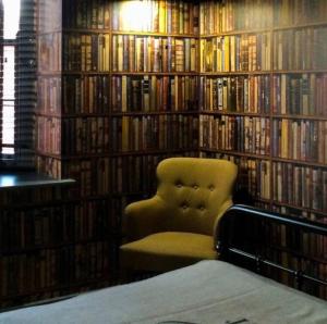 a library with a chair in front of a book shelf at The Black Hole in Winchester