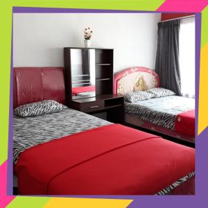 a bedroom with two beds and a dresser and a mirror at De'Vita Family Homestay in Malang