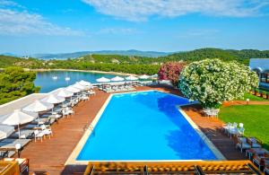 an outdoor swimming pool with chairs and umbrellas at Skiathos Palace Hotel in Koukounaries