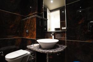 a bathroom with a sink and a toilet and a mirror at Hotel Varanasi Heritage in Varanasi