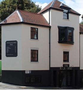 a white building with black windows on a street at The Black Hole in Winchester