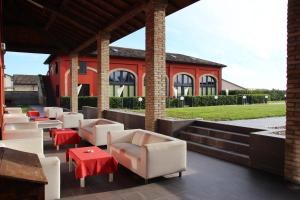 un patio con sillas y mesas blancas y un edificio en Corte Di Frara, en Parma