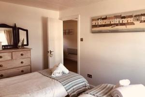 a bedroom with a bed and a dresser and a mirror at Bay House Lundy Port Isaac Apartment with Sea Views in Port Isaac