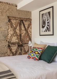 um quarto com uma cama branca e uma parede de tijolos em Porto River em Porto