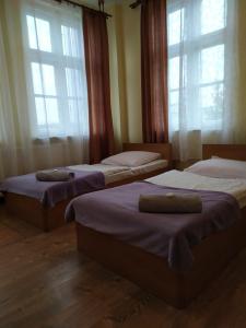 two beds in a room with two windows at Dom Turysty in Kostrzyn nad Odrą