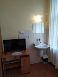 baño con lavabo y mesa con TV. en Dom Turysty en Kostrzyn nad Odrą