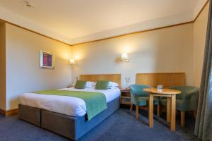 a hotel room with a bed and a table and chairs at Tullamore Court Hotel in Tullamore