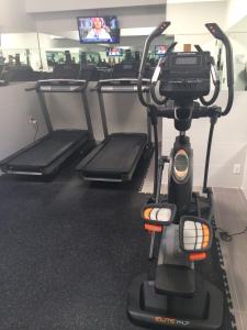 a gym with three treadmills in a room at Pointe Plaza Hotel in Brooklyn