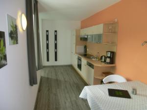 eine Küche mit orangefarbenen Wänden und einem Tisch im Zimmer in der Unterkunft Kleeblatthaus Putbus Rügen in Putbus