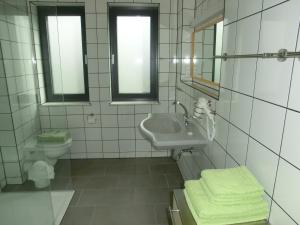 La salle de bains blanche est pourvue d'un lavabo et de toilettes. dans l'établissement Kleeblatthaus Putbus Rügen, à Putbus