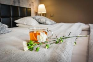a cup of tea and flowers on a bed at Willa Bryza in Gdynia