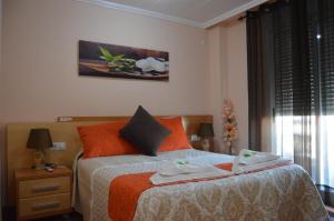 a bedroom with a bed with orange pillows at Hostal Carrizo in Elda