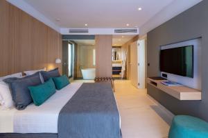 a bedroom with a large bed and a flat screen tv at Skiathos Palace Hotel in Koukounaries