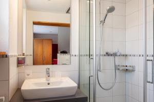 
a bathroom with a shower, sink, and mirror at Hotel Jägerhof in Zermatt
