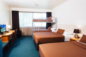 Habitación de hotel con 2 literas y escritorio. en City Oasis Inn en Townsville