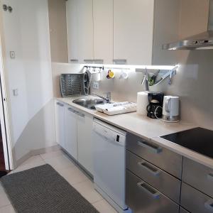 una pequeña cocina con armarios blancos y fregadero en apartment luxe MMR en Barcelona