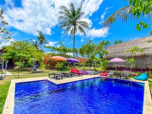 una piscina con sillas y sombrillas frente a una casa en Namaste Bungalows, en Nusa Penida